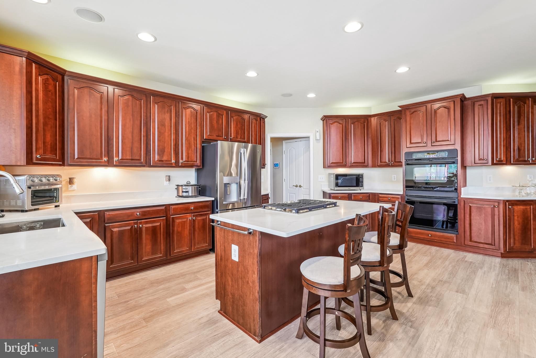 42801 Ridgeway Drive Broadlands, VA 20148 - Photo 10 of 40 a kitchen with stainless steel appliances granite countertop a stove top oven a refrigerator a sink and a microwave with wooden floor