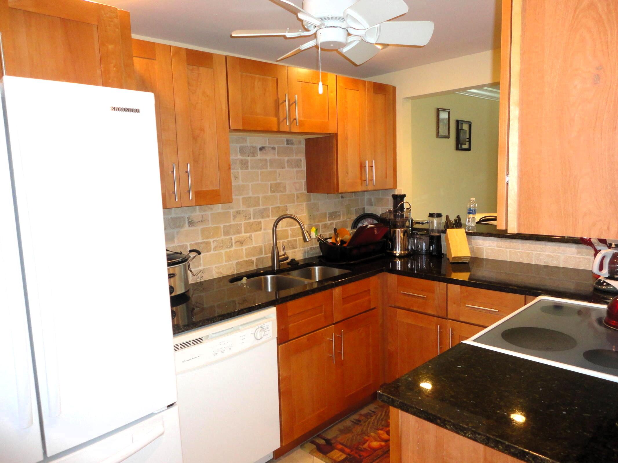 5433 Southeast Miles Grant Road, Unit E104 Stuart, FL 34997 - Photo 7 of 16 a kitchen with stainless steel appliances a sink and a refrigerator