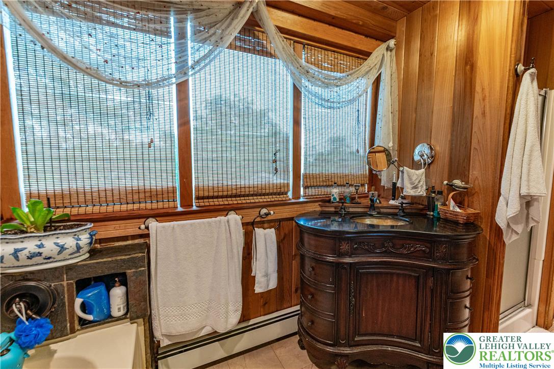 2485 Hieter Road Quakertown, PA 18951 - Photo 32 of 97 A charming bathroom features wood paneling and a unique carved vanity with dual sinks.