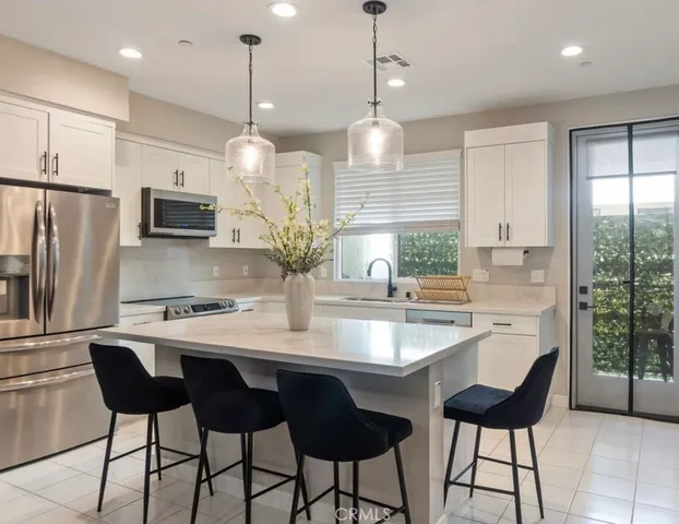 a kitchen with stainless steel appliances granite countertop a sink a stove a refrigerator and island with wooden floor