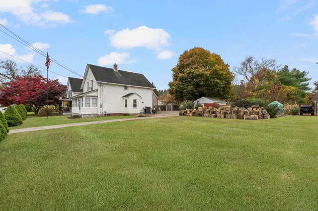 a view of a white house with a big yard and large trees