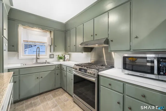 a kitchen with stainless steel appliances granite countertop a stove a sink and a microwave