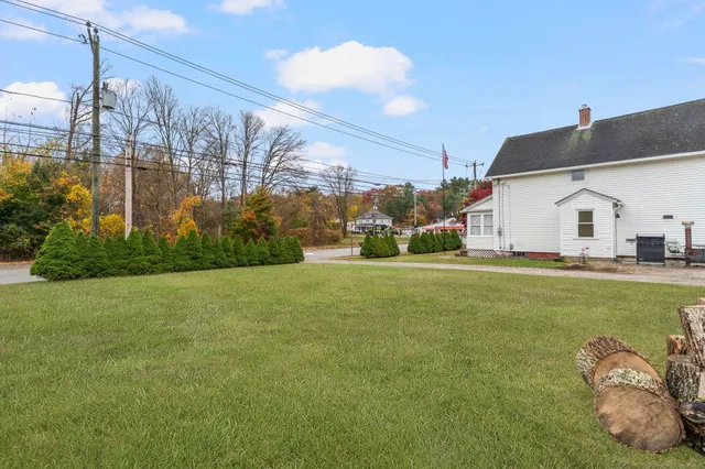 a view of a white house with a big yard and potted plants