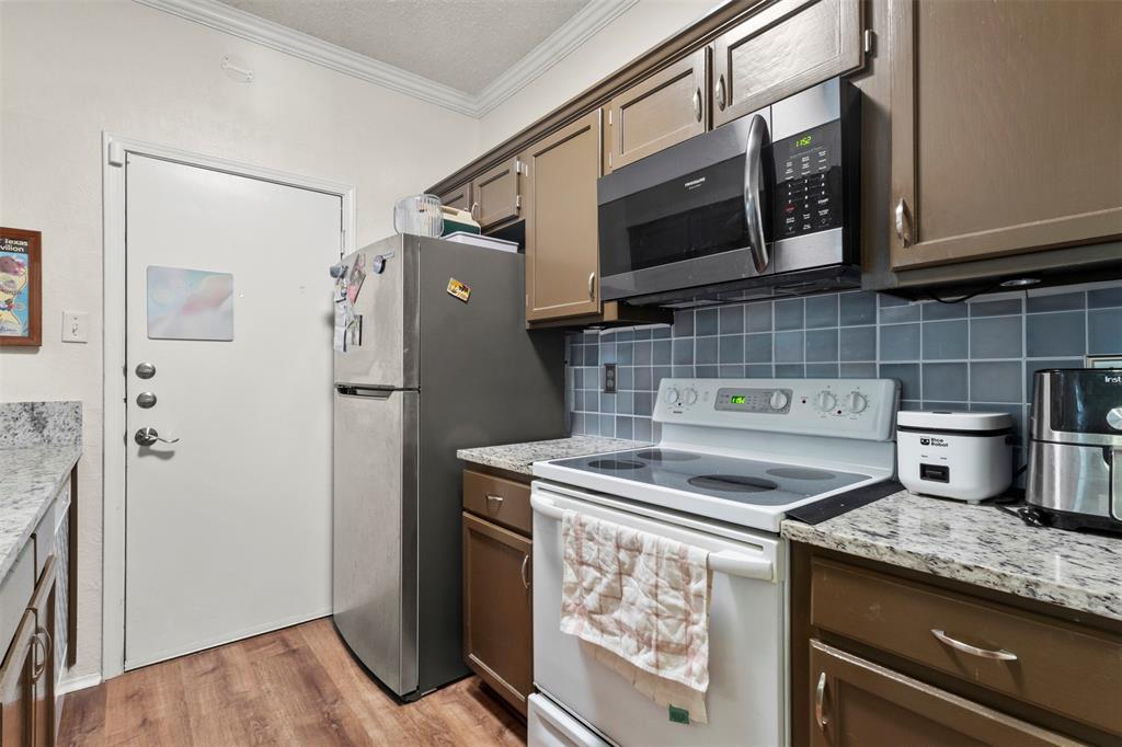 5616 Preston Oaks Road, Unit 1105 Dallas, TX 75254 - Photo 10 of 17 a kitchen with stainless steel appliances granite countertop a refrigerator and a stove top oven