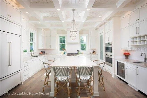 a kitchen with stainless steel appliances a dining table chairs refrigerator and cabinets