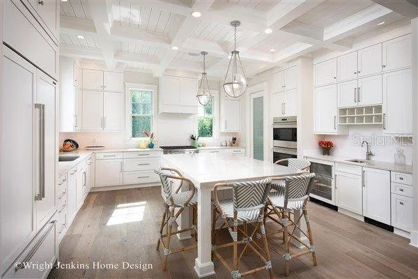 a kitchen with stainless steel appliances kitchen island granite countertop a table chairs sink and cabinets