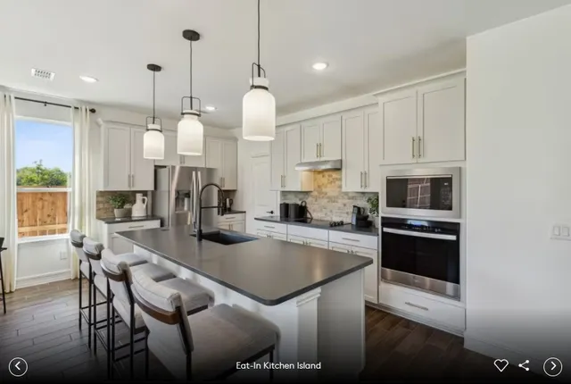 a large kitchen with stainless steel appliances a stove sink and white cabinets