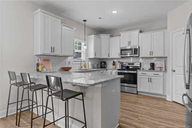 a kitchen with granite countertop white cabinets and stainless steel appliances