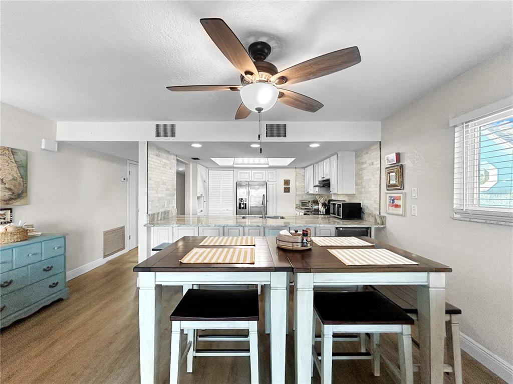 2505 Bay Boulevard, Unit 1 Indian Rocks Beach, FL 33785 - Photo 14 of 25 a open kitchen with stainless steel appliances kitchen island granite countertop a stove a refrigerator a oven a dining table and chairs with wooden floor