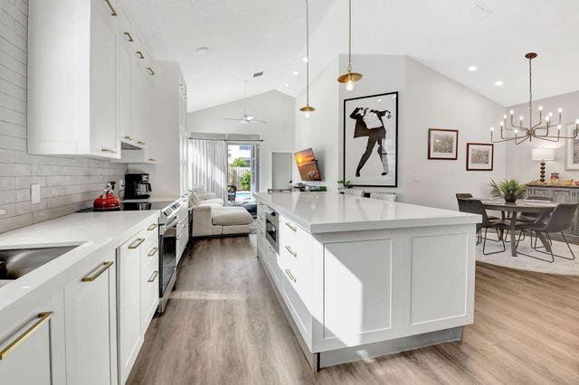 a large white kitchen with stainless steel appliances lots of counter space and wooden floor