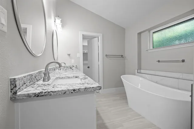 a bathroom with a granite countertop sink a mirror and a bathtub