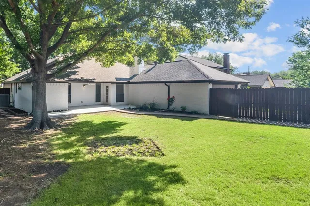 a backyard of a house with lawn chairs and wooden fence