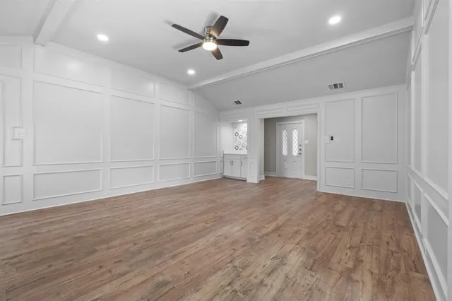 a view of empty room with wooden floor and ceiling fan