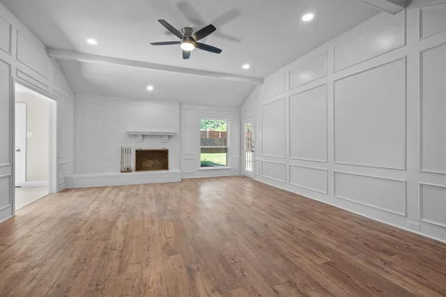 an empty room with wooden floor fireplace and windows