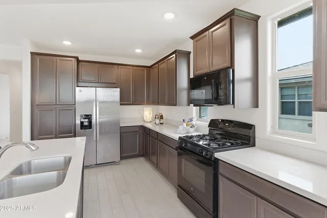 a kitchen with stainless steel appliances granite countertop a refrigerator a sink and a stove