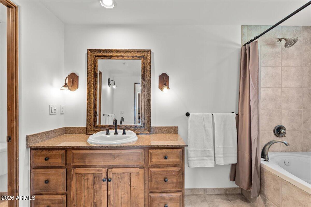 36601 North Mule Train Road, Unit C16 Carefree, AZ 85377 - Photo 15 of 38 a bathroom with a granite countertop sink a mirror a bathtub and shower