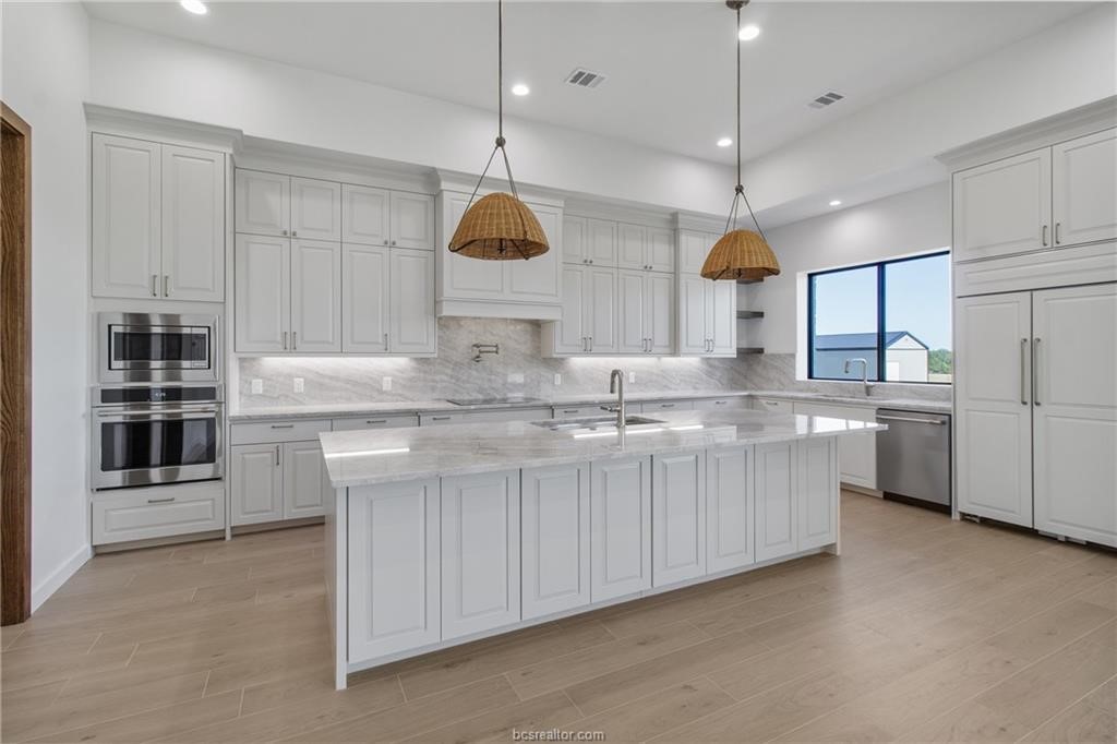 4558 Hicks Lane Bryan, TX 77845 - Photo 11 of 48 a kitchen with stainless steel appliances granite countertop a sink a stove and a refrigerator