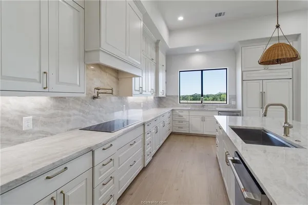 a kitchen with granite countertop a sink a counter space appliances and cabinets