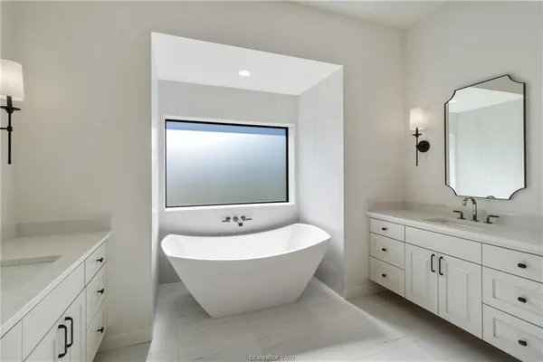 a spacious bathroom with a double vanity sink mirror and bathtub