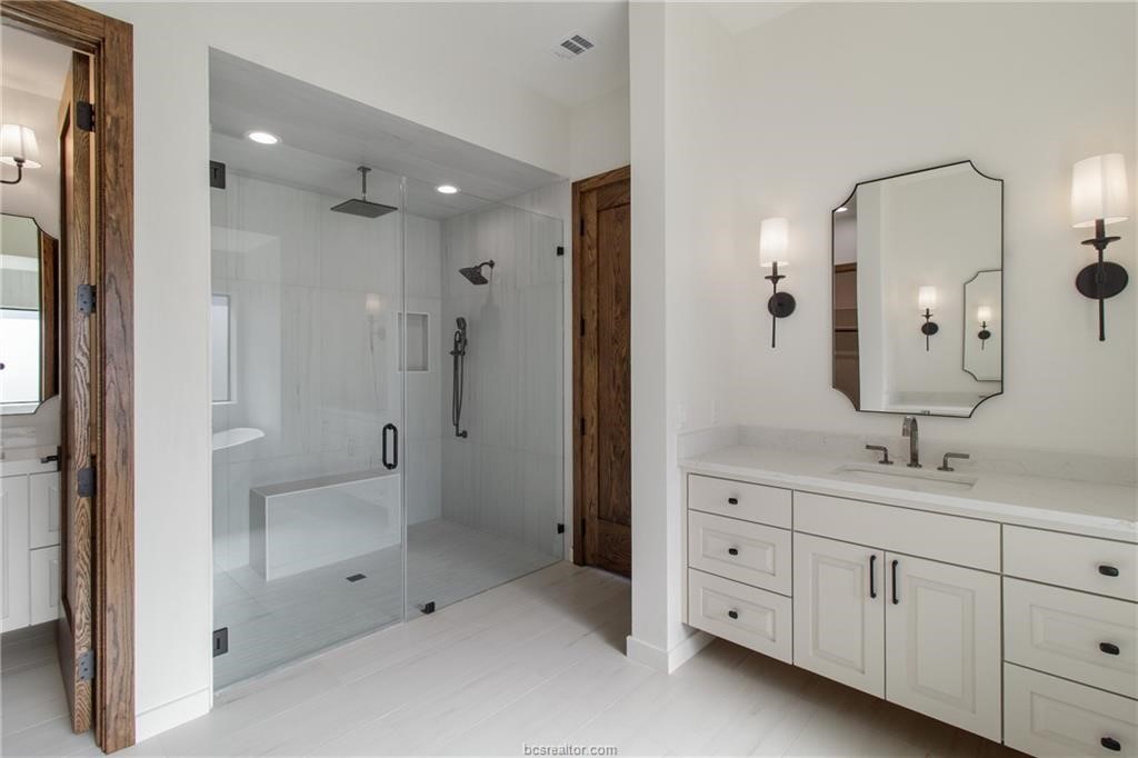 4558 Hicks Lane Bryan, TX 77845 - Photo 32 of 48 a spacious bathroom with a double vanity sink a large mirror and shower