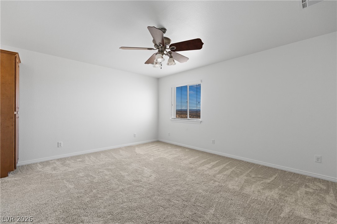 575 Gann Avenue Logandale, NV 89021 - Photo 43 of 75 A spacious, naturally illuminated room features plush carpeting and a convenient ceiling fan.