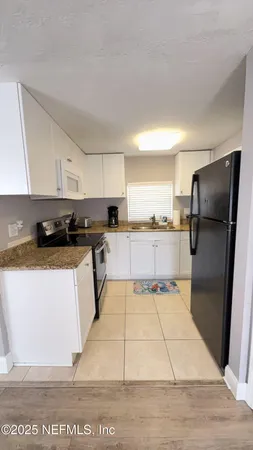 a kitchen with granite countertop a refrigerator and a stove top oven
