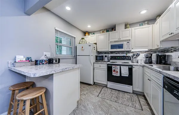a kitchen with granite countertop a refrigerator stove top oven and sink