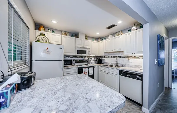 a kitchen with stainless steel appliances granite countertop a refrigerator sink and stove