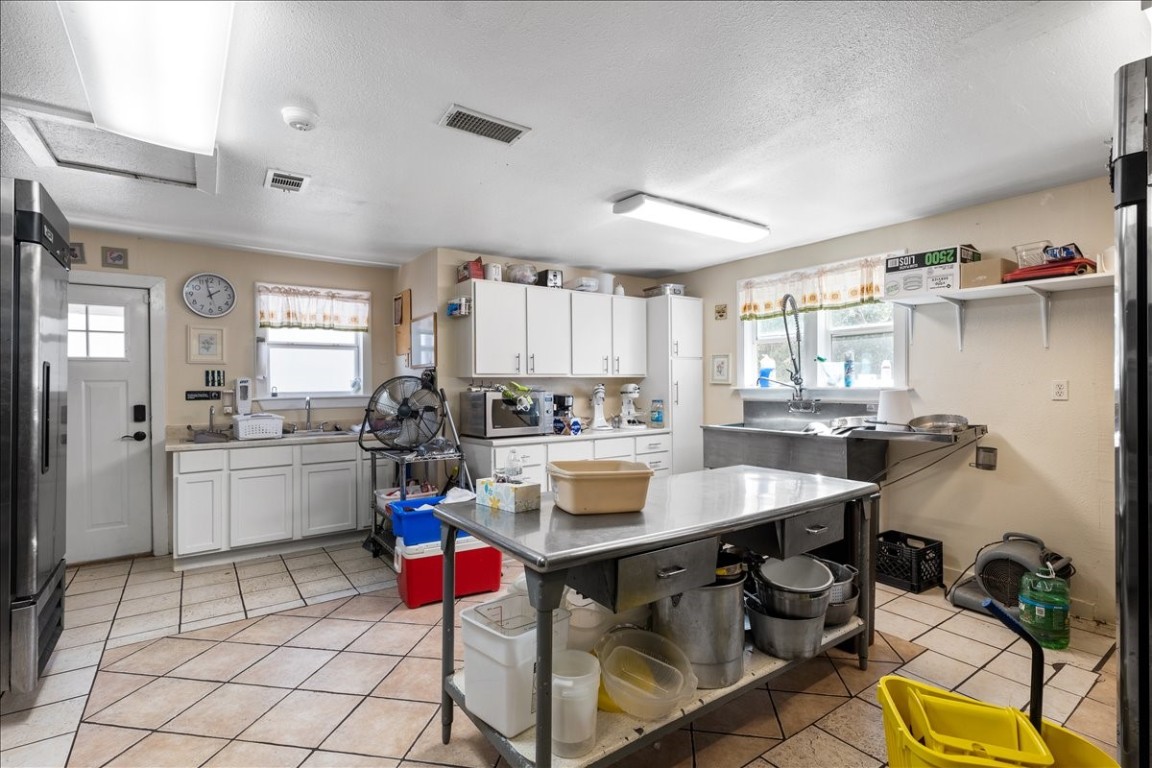 2606 Santa Rosa Street Austin, TX 78702 - Photo 17 of 28 Kitchen featuring white cabinetry, appliances with stainless steel finishes, sink, and light tile patterned floors