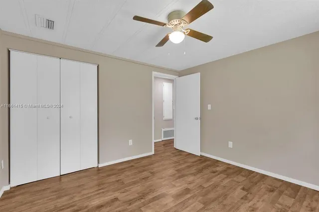 an empty room with wooden floor fan and windows