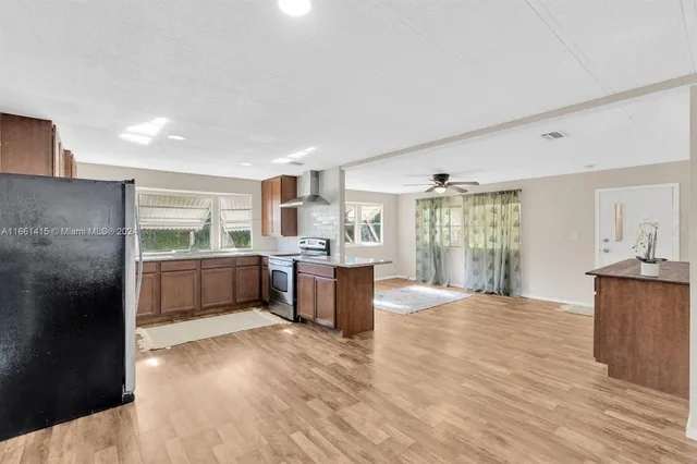 a kitchen with stainless steel appliances kitchen island granite countertop a stove a refrigerator a sink dishwasher with a oven and cabinets with wooden floor