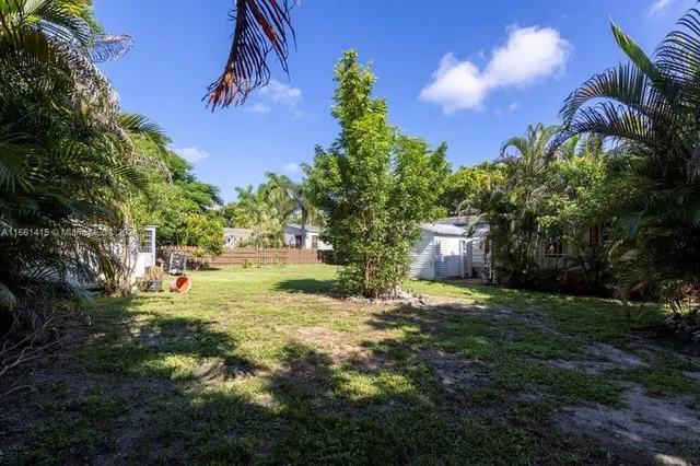 a backyard of a house with table and chairs plants and large tree