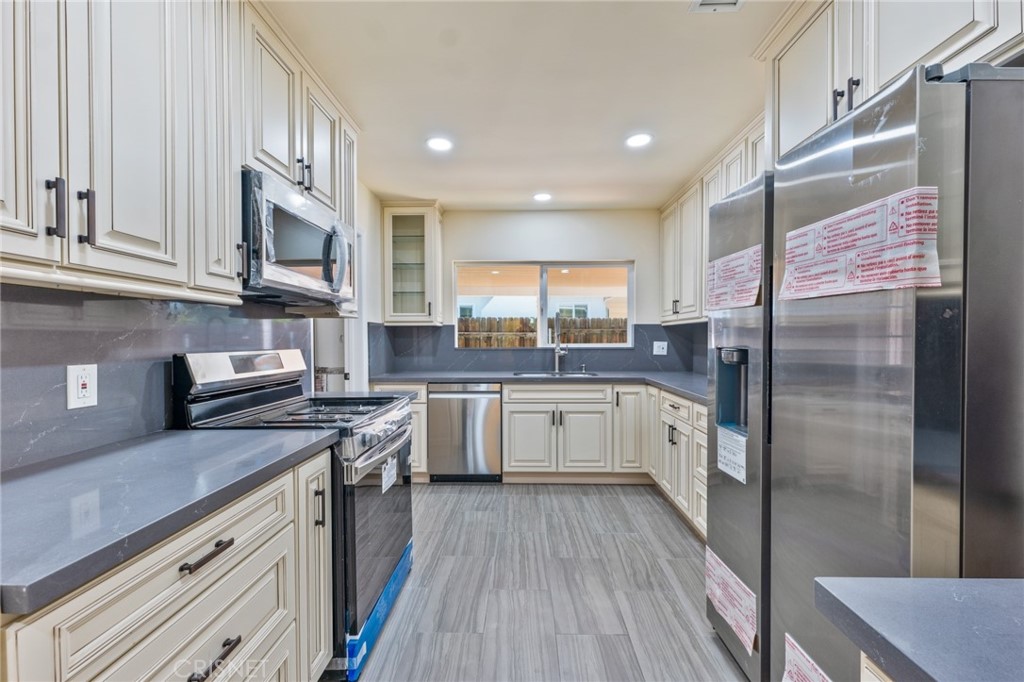 17604 Willard Street Northridge, CA 91325 - Photo 7 of 28 a kitchen with stainless steel appliances granite countertop a stove a sink dishwasher a refrigerator and white cabinets with wooden floor