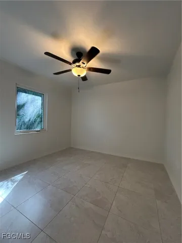 an empty room with a ceiling fan and window