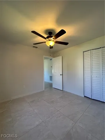 an empty room with closet and a ceiling fan