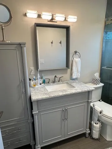 a bathroom with a granite countertop sink a toilet and a mirror
