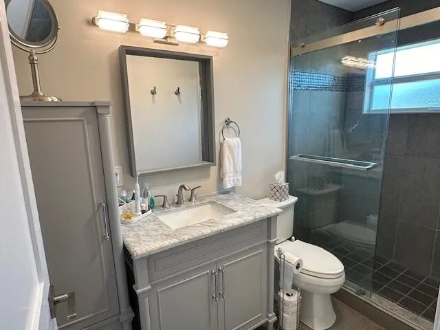 a bathroom with a granite countertop toilet sink and mirror