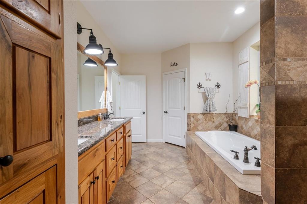 318 East Lone Star Road Poolville, TX 76487 - Photo 11 of 33 a bathroom with a granite countertop tub sink and mirror