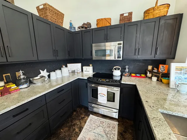 a kitchen with stainless steel appliances granite countertop a sink stove and cabinets