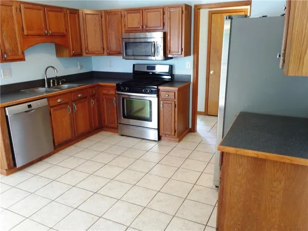 a kitchen with stainless steel appliances a sink a stove a refrigerator cabinets and a counter top space