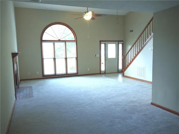an empty room with windows and chandelier fan