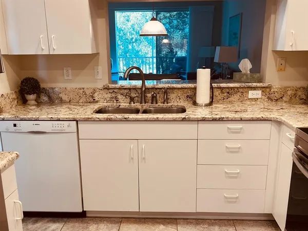 a kitchen with granite countertop white cabinets and a sink