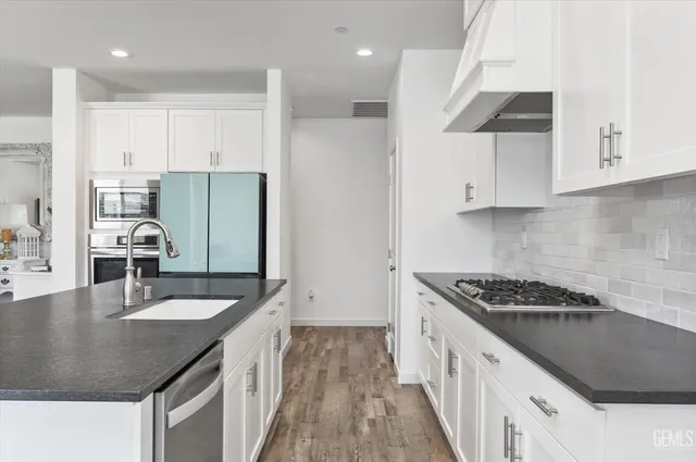 a kitchen with stainless steel appliances a stove a microwave and a hard wood floors