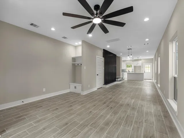 an empty room with wooden floor and windows