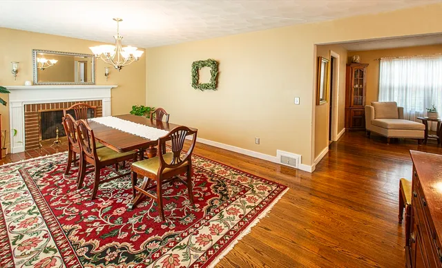 a dining room with wooden floor a chandelier a wooden table and chairs