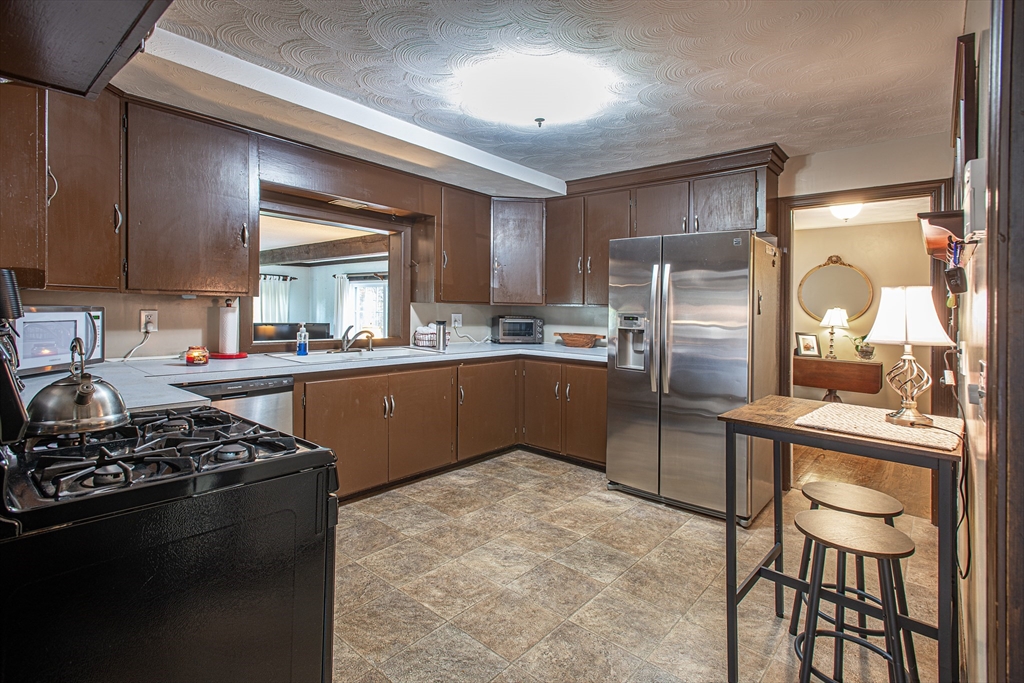 54 South Shore Drive Springfield, MA 01118 - Photo 9 of 39 a kitchen with stainless steel appliances granite countertop a stove a sink dishwasher a refrigerator and a dining table with wooden cabinet