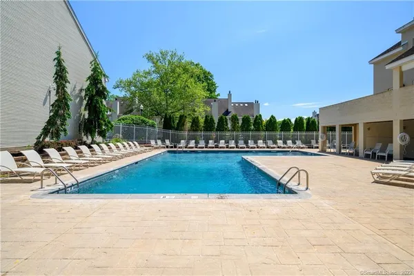 a view of swimming pool with outdoor seating and trees in the background