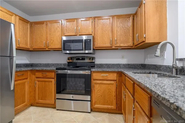 a kitchen with stainless steel appliances granite countertop a stove a sink and a microwave
