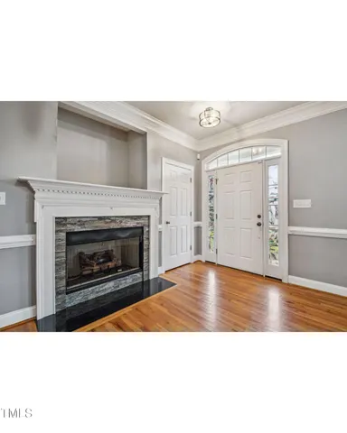 a view of an empty room with wooden floor fireplace and a window
