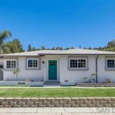 a view of a yard in front of a house with large windows